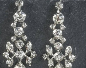 May include: A pair of silver dangle earrings with a cluster of clear rhinestones in a floral design.