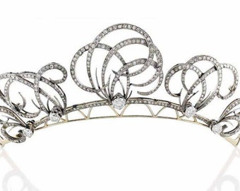 Könnte beinhalten: Eine silberne und Diamanten-Tiara mit einem zarten, komplizierten Design. Die Tiara zeigt eine Reihe von wirbelnden, floral inspirierten Motiven, die mit funkelnden Diamanten besetzt sind.