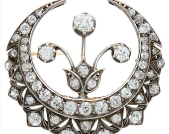 May include: A silver crescent moon brooch with a floral design, set with sparkling diamonds.