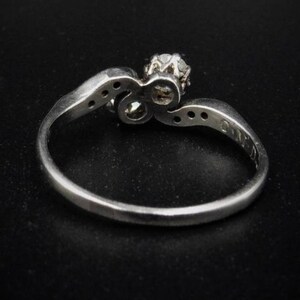 May include: A silver ring with a single diamond set in a twisted band. The ring is set with smaller diamonds on the band.