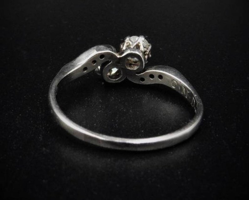 May include: A silver ring with a single diamond set in a twisted band. The ring is set with smaller diamonds on the band.