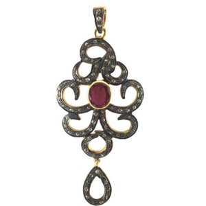 May include: A silver and gold pendant with a red gemstone in the center and a teardrop-shaped pendant hanging from the bottom.