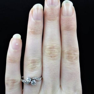 May include: A silver ring with two round diamonds set in a twisted band.
