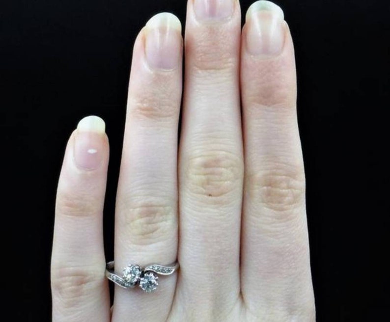 May include: A silver ring with two round diamonds set in a twisted band.
