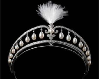 May include: A silver tiara with a white feather on top and a row of pearlescent beads around the band.