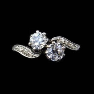 May include: A silver ring with two round diamonds set in a swirling design.