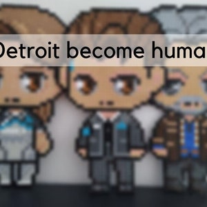 May include: Three pixel art figures from the video game Detroit: Become Human. The figures are of Connor, Kara, and Markus. Connor is wearing a black suit and tie, Kara is wearing a white and blue outfit, and Markus is wearing a brown jacket and blue shirt.