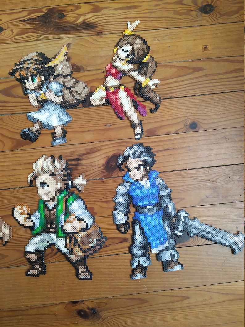 Puede incluir: Cuatro figuras de pixel art hechas con cuentas de colores. Las figuras son una mujer con un vestido rojo, una mujer con un vestido blanco, un hombre con un chaleco verde y un hombre con armadura azul.