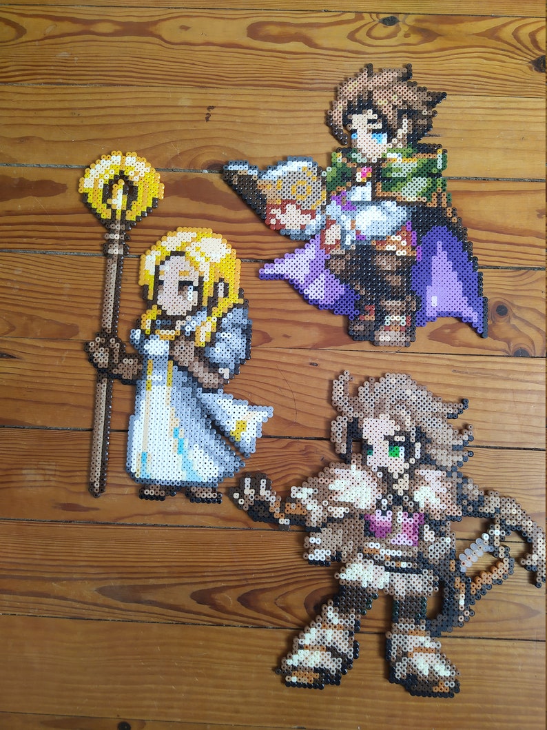 Puede incluir: Tres figuras de pixel art hechas de cuentas de colores. Las figuras son una mujer con cabello rubio sosteniendo un bast&oacute;n, un hombre con cabello casta&ntilde;o sosteniendo un libro y una mujer con cabello casta&ntilde;o sosteniendo un arco y una flecha.