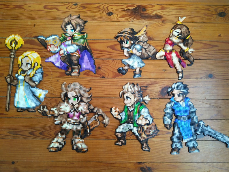 Puede incluir: Un conjunto de ocho figuras de pixel art, cada una representando un personaje diferente. Las figuras est&aacute;n hechas de cuentas de colores y est&aacute;n dispuestas sobre una superficie de madera. Los personajes incluyen una guerrera con una espada, un mago con un bast&oacute;n, una arquera con un arco y flechas, un caballero con un escudo, una sanadora con un bast&oacute;n, un ladr&oacute;n con una daga, una bardo con un la&uacute;d y un monje con un bast&oacute;n.