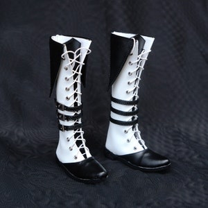 May include: A pair of white and black knee-high boots with black buckles and laces.