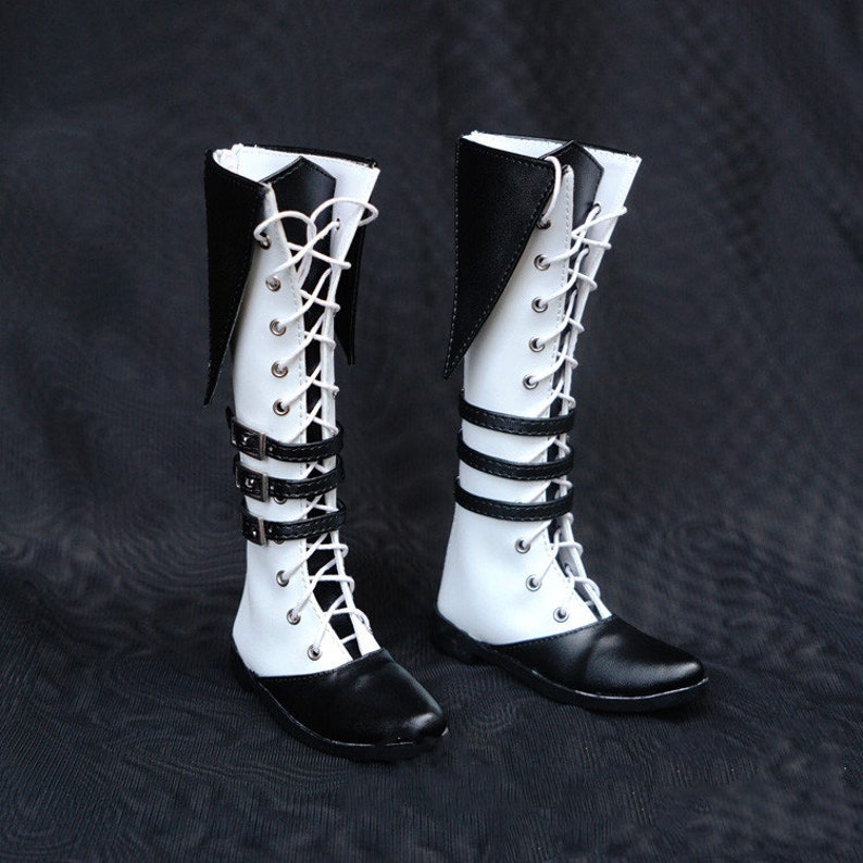 May include: A pair of white and black knee-high boots with black buckles and laces.