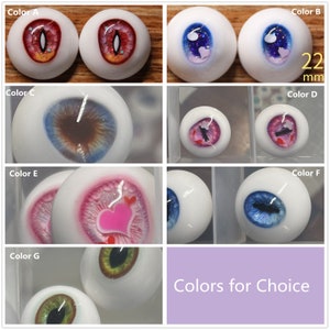 May include: A selection of 22 mm doll eyes in various colors and designs, including red, blue, green, pink, and brown. The eyes are arranged in a grid with labels for each color.