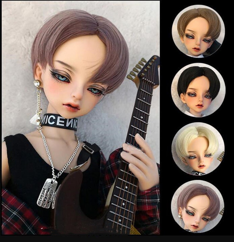 May include: A doll with a short, straight, light brown wig with a side part. The doll is wearing a black shirt, a silver chain necklace with a dog tag, and a black choker with the word "NICE" on it. The doll is holding a guitar.