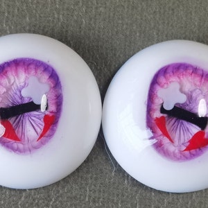 May include: A pair of purple and pink doll eyes with a black pupil and red accents. The eyes have a white sclera and a white star-shaped design.
