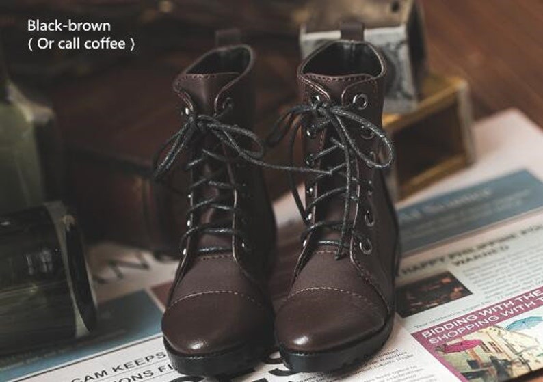 May include: A pair of brown leather lace-up boots with black laces. The boots have a slightly distressed look and are sitting on a newspaper.
