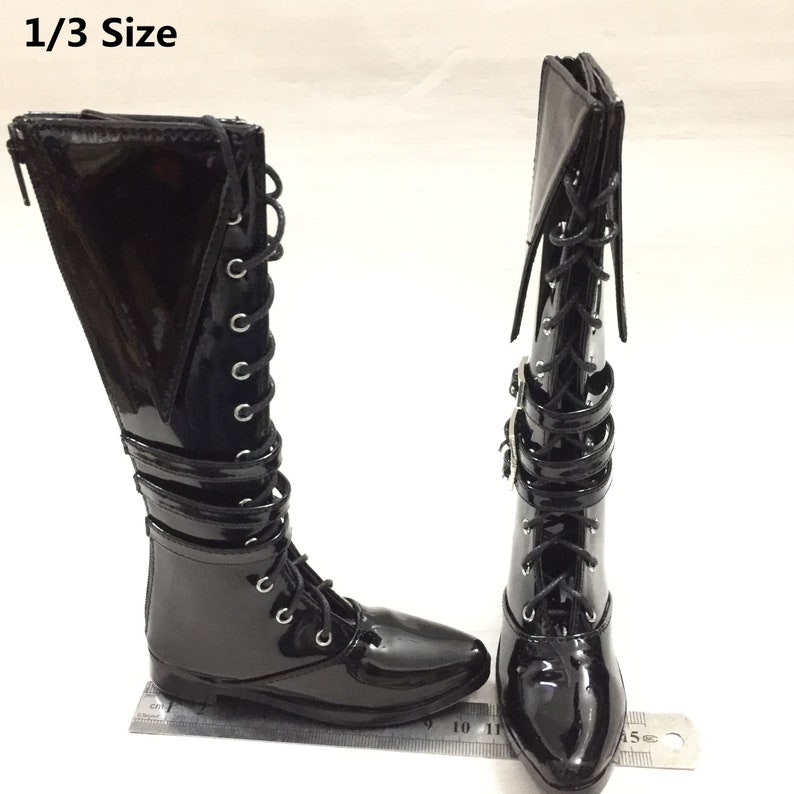 May include: A pair of black patent leather knee-high boots with lace-up fronts and buckle accents. The boots have a pointed toe and a low heel. The boots are 1/3 size.