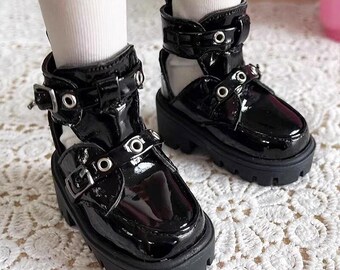 May include: A pair of black patent leather ankle boots with buckles and cutouts. The boots have a chunky platform sole and a lace-up closure.