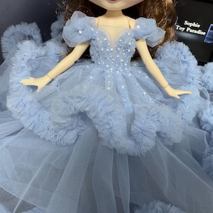 May include: A light blue tulle dress with a ruffled skirt and beaded bodice. The dress is designed for a doll.