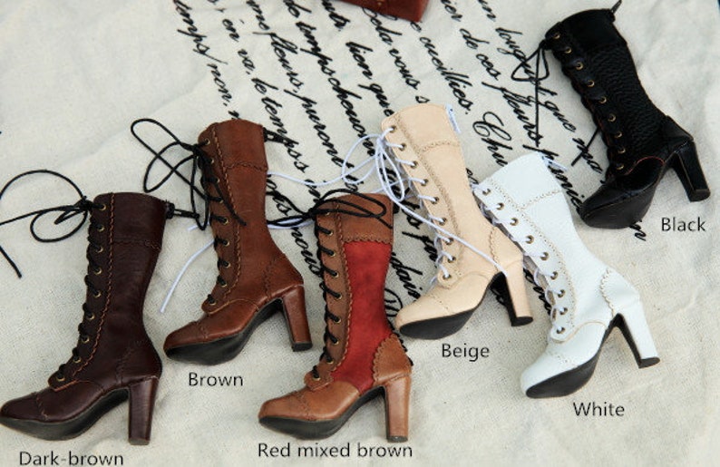 May include: A selection of high-heeled, lace-up boots in shades of dark brown, brown, red mixed brown, beige, white, and black. The boots feature a classic design with a pointed toe and a sturdy heel. The boots are displayed on a patterned fabric.
