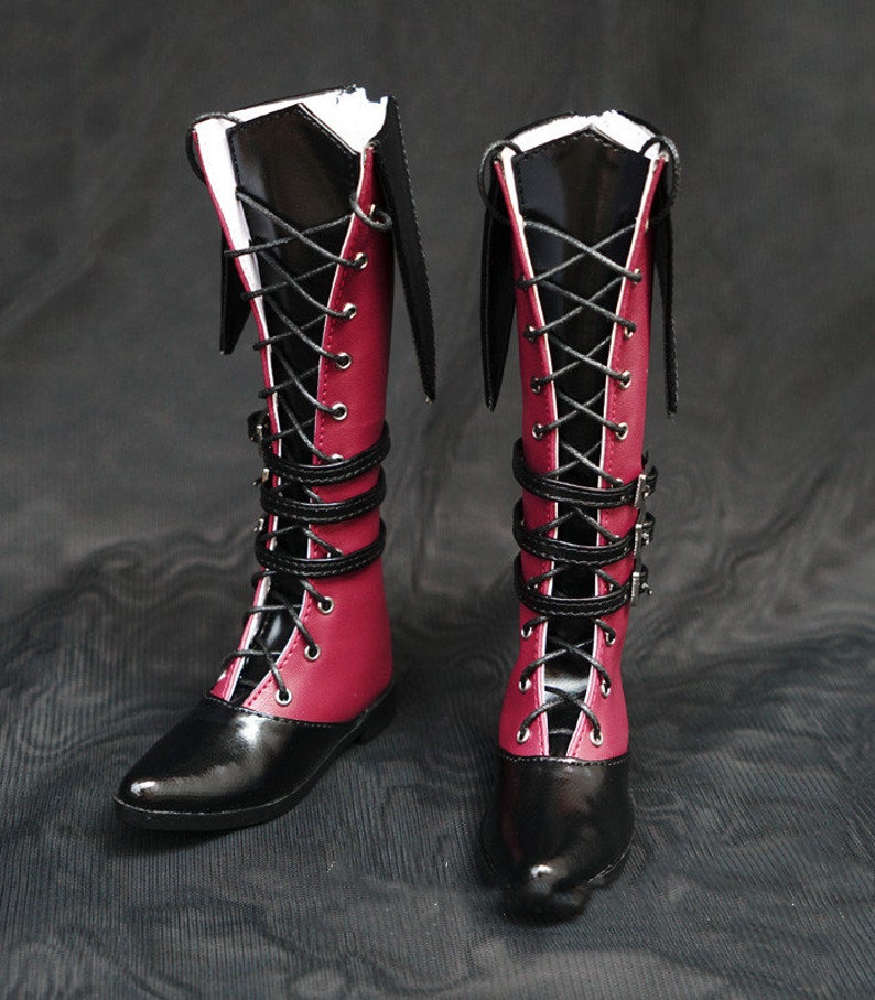 May include: A pair of black and burgundy knee-high boots with lace-up fronts and buckle straps.