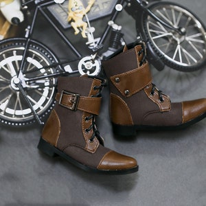 May include: A pair of brown leather ankle boots with laces and buckles. The boots have a brown canvas upper and a brown leather toe cap.