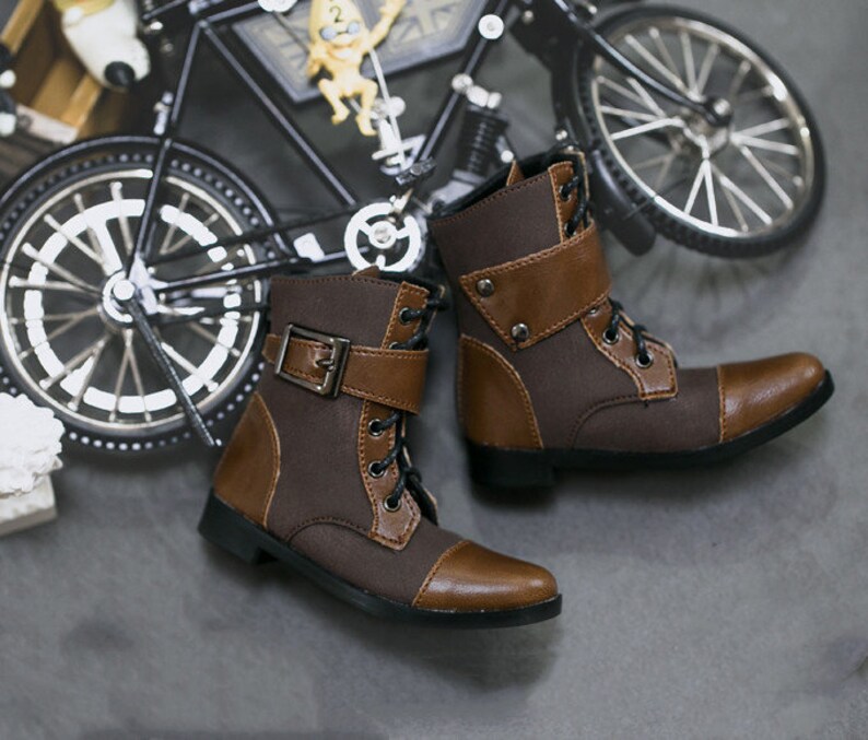 May include: A pair of brown leather ankle boots with laces and buckles. The boots have a brown canvas upper and a brown leather toe cap.