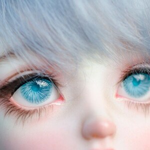 K&ouml;nnte beinhalten: Nahaufnahme eines Puppenkopfes mit blauen Augen und hellblauem Haar.