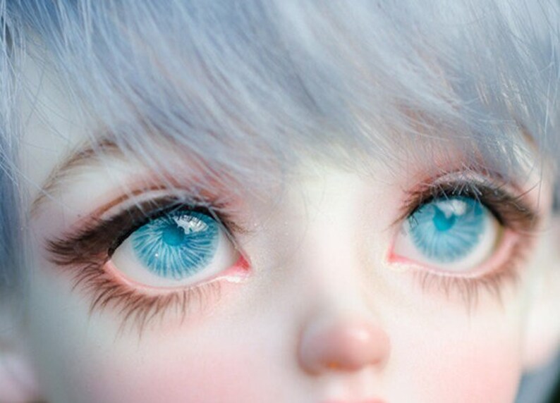 K&ouml;nnte beinhalten: Nahaufnahme eines Puppenkopfes mit blauen Augen und hellblauem Haar.