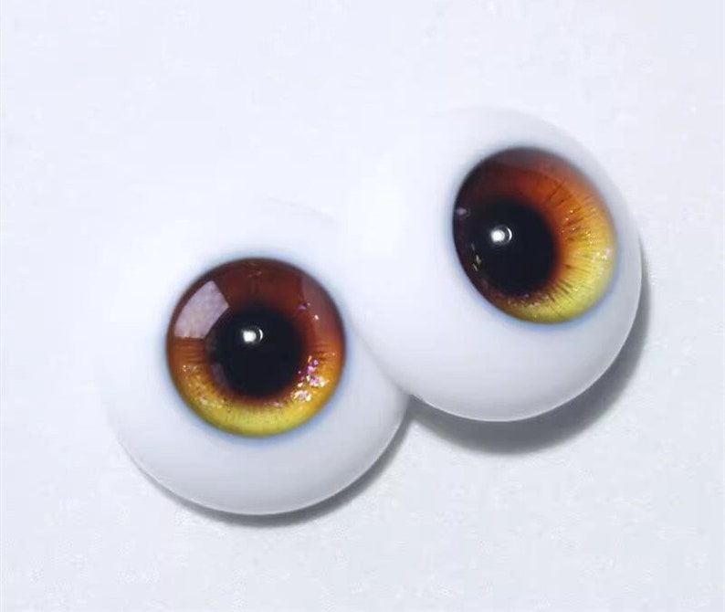 Peut inclure: Une paire d'yeux de poup&eacute;e r&eacute;alistes avec un iris brun et jaune et une pupille noire.
