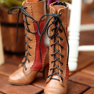 May include: A pair of brown and red lace-up boots with a scalloped edge design. The boots have a pointed toe and a small heel. Black laces are threaded through brass eyelets. The boots are made of leather and have a vintage aesthetic.