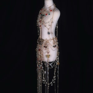 May include: A gold-toned body chain with red, green, and clear beads and crystals. The chain is layered and has a long, flowing skirt-like bottom.