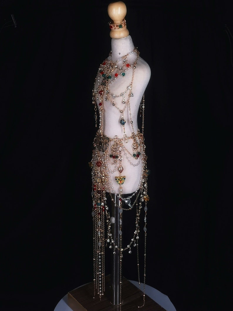 May include: A gold-toned body chain with red, green, and clear beads and crystals. The chain is layered and has a long, flowing skirt-like bottom.