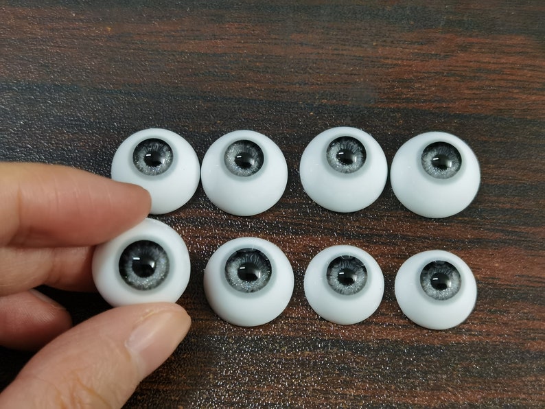 May include: Eight gray and white doll eyes with black pupils. The eyes are arranged in two rows of four.