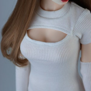 May include: White ribbed knit crop top with a cutout detail at the front. The top has short sleeves and a high neckline.