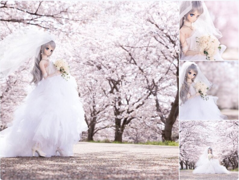 May include: A white bridal doll with long, silver hair and a white wedding dress, holding a bouquet of white flowers. The doll is standing in front of a background of pink cherry blossoms.