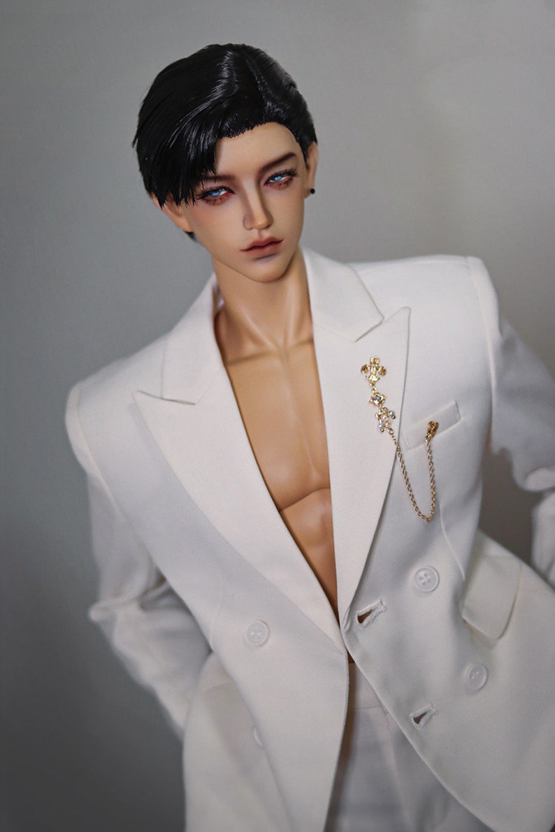 May include: A white double-breasted blazer with a gold chain and a decorative pin. The blazer has a sharp, tailored look.