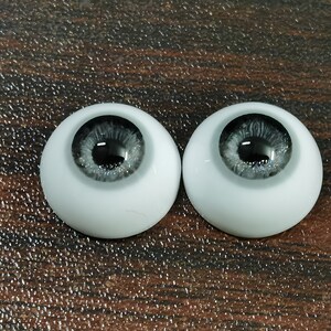 May include: Two white doll eyes with a black pupil and a silver glitter iris.