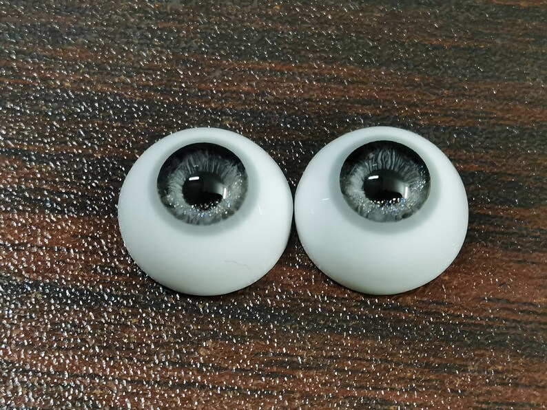 May include: Two white doll eyes with a black pupil and a silver glitter iris.