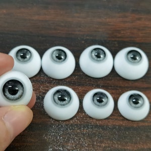 May include: Eight white doll eyes with black and silver irises. The eyes are arranged in two rows of four.