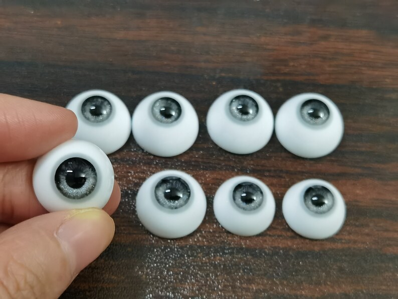 May include: Eight white doll eyes with black and silver irises. The eyes are arranged in two rows of four.