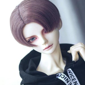 May include: A doll with a short, straight, purple wig. The wig has a side part and is styled with a slight curve at the ends. The doll is wearing a black hoodie with white text that says "NICE NICE".