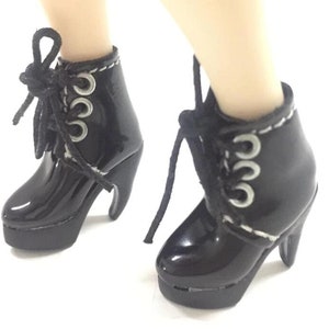 May include: Black patent leather ankle boots with silver eyelets and laces. The boots have a chunky heel and a platform.