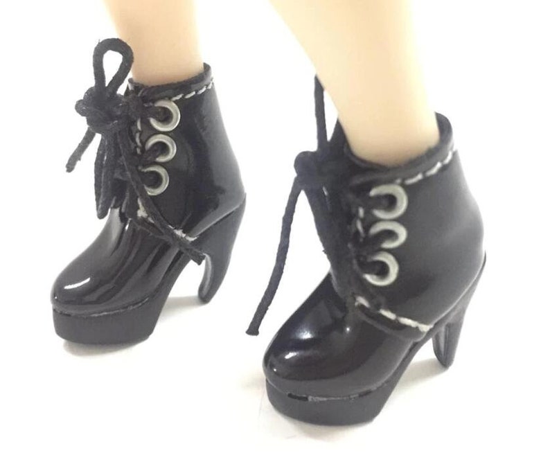 May include: Black patent leather ankle boots with silver eyelets and laces. The boots have a chunky heel and a platform.