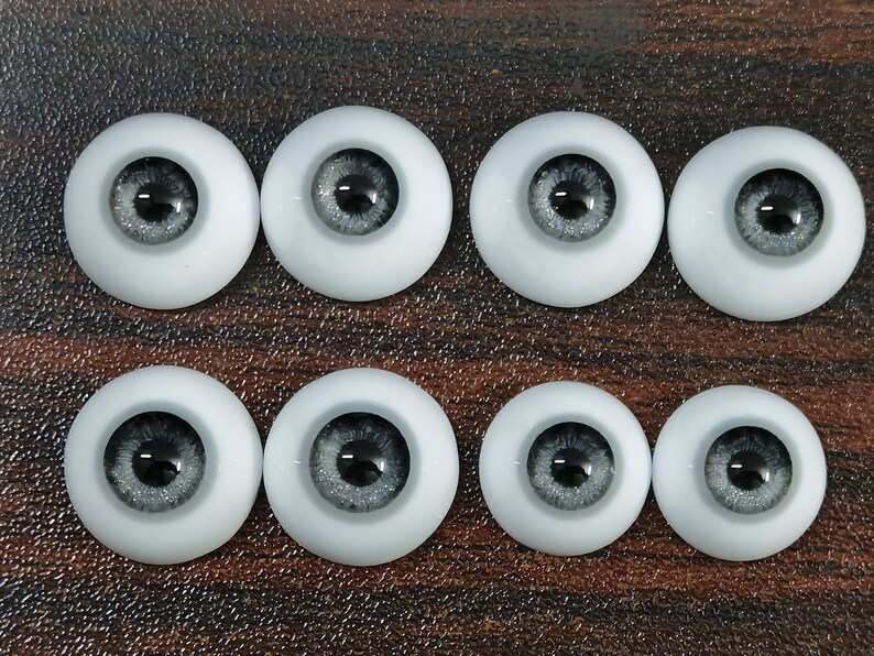 May include: Eight pairs of gray and black doll eyes with a glitter finish. The eyes are round and have a black pupil.