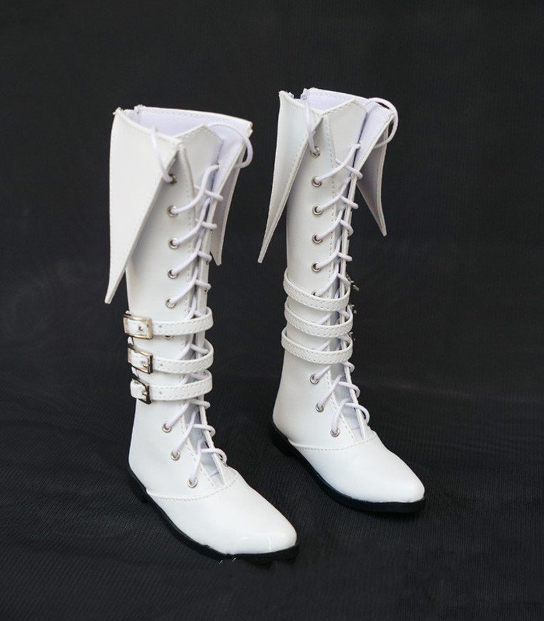 May include: A pair of white knee-high boots with lace-up fronts and buckle straps. The boots have pointed toes and a slightly flared top.