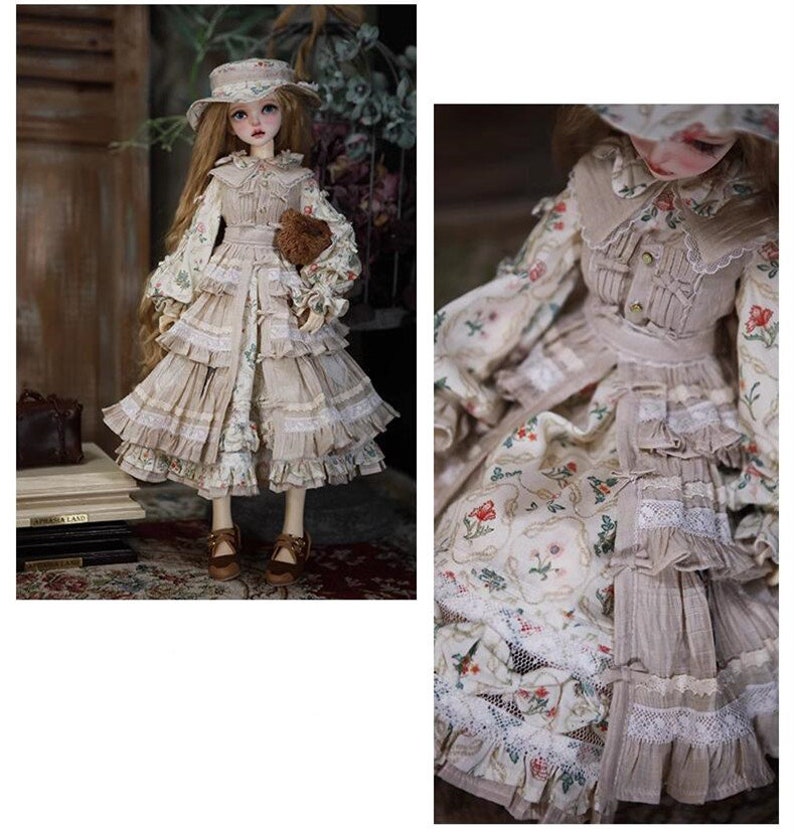 May include: A doll wearing a beige dress with floral print and lace trim. The dress has a ruffled skirt and a matching hat. The doll is holding a small brown teddy bear.