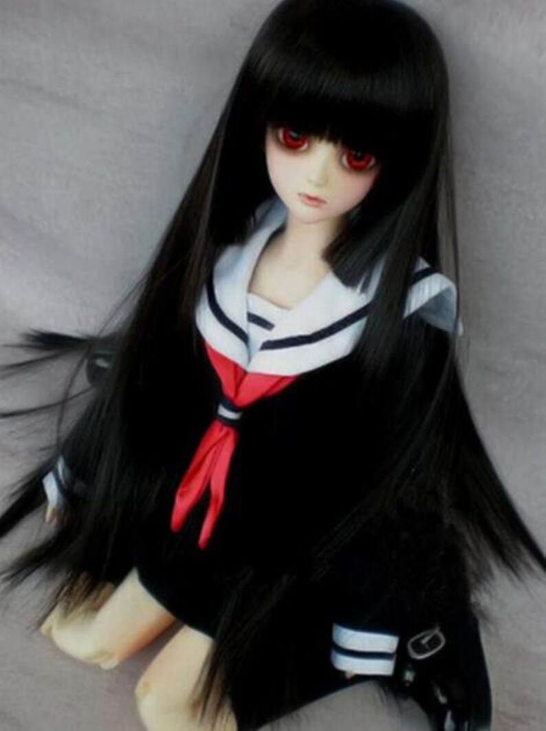 May include: A black haired doll with red eyes wearing a black and white sailor uniform with a red bow tie.