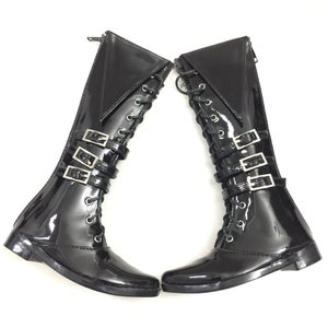 May include: Pair of black patent leather knee-high boots with silver buckles and lace-up fronts.