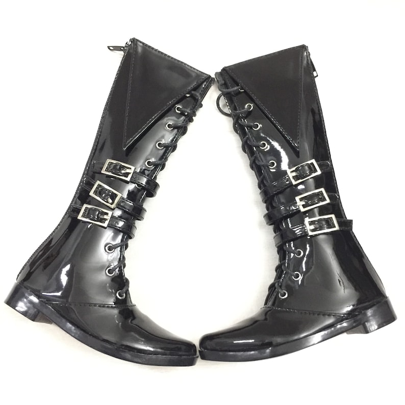 May include: Pair of black patent leather knee-high boots with silver buckles and lace-up fronts.